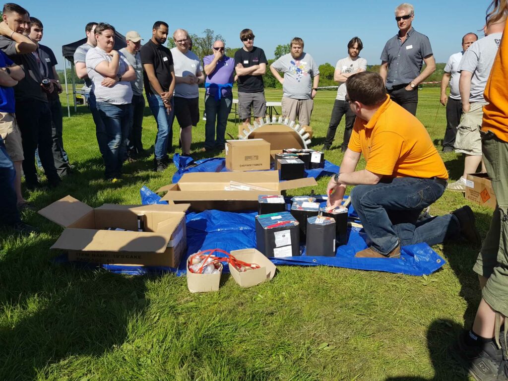 different fireworks laid out on the ground being shown to a group
