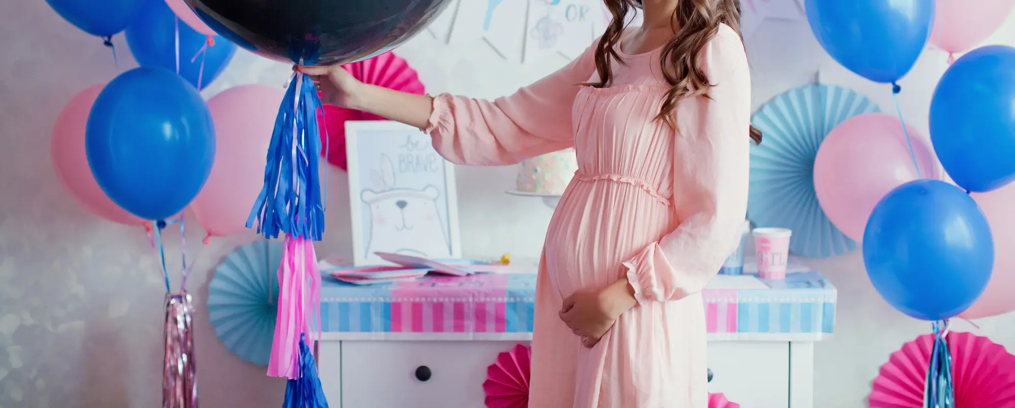 Women holding balloon at gender reveal party