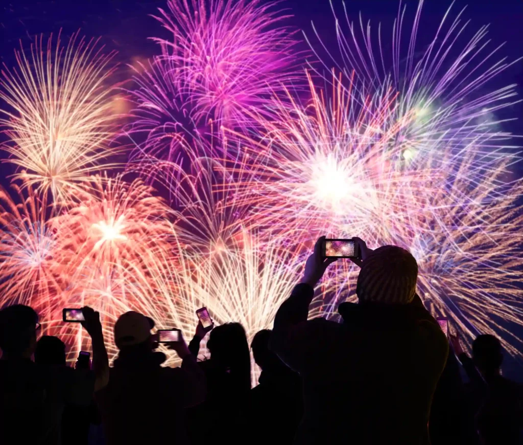 Group of people watching fireworks taking photos on mobile phones