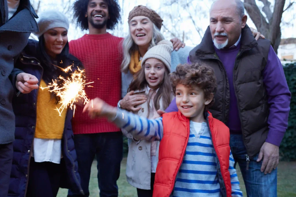 young boy holding sparklers in the family garden enjoying bonfire night